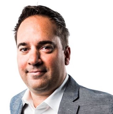 a man in a suit and tie smiling at the camera